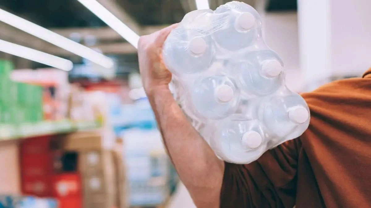 UE a anunțat un plan de protecție a populației în caz de cel mai grav scenariu. În imagine, un bărbat într-un supermarket purtând o sticlă de apă pe umăr