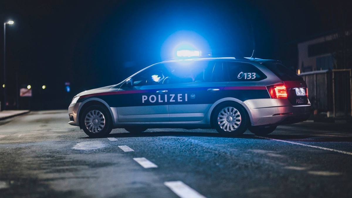 Mașină a poliției austriece cu girofarul albastru aprins, pe o stradă noaptea