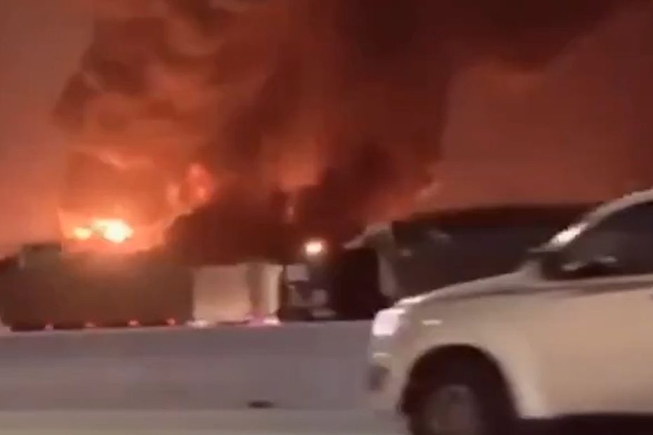 Incendiu puternic în timpul nopții, cu flăcări uriașe și coloane dense de fum negru, surprins de pe o șosea din Arabia Saudită.