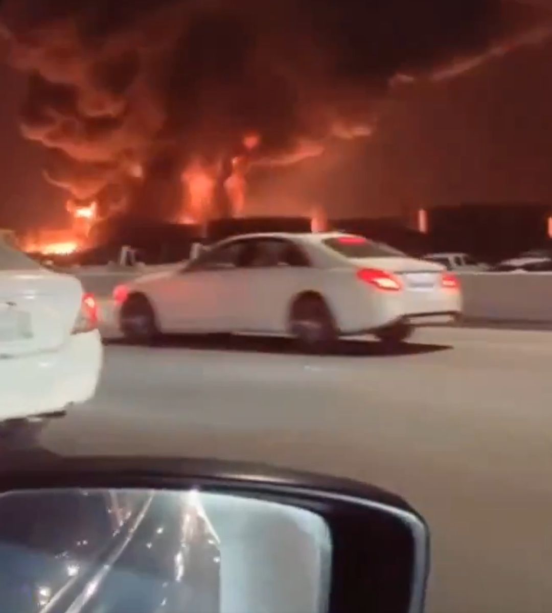 Incendiu de amploare filmat din trafic, cu flăcări și fum dens pe cerul nopții, în apropierea mai multor autoturisme.