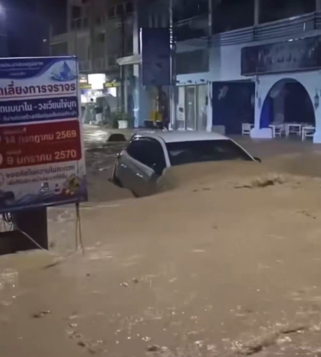 Autoturism parțial scufundat în apa noroioasă pe o stradă inundată din Patong, Phuket