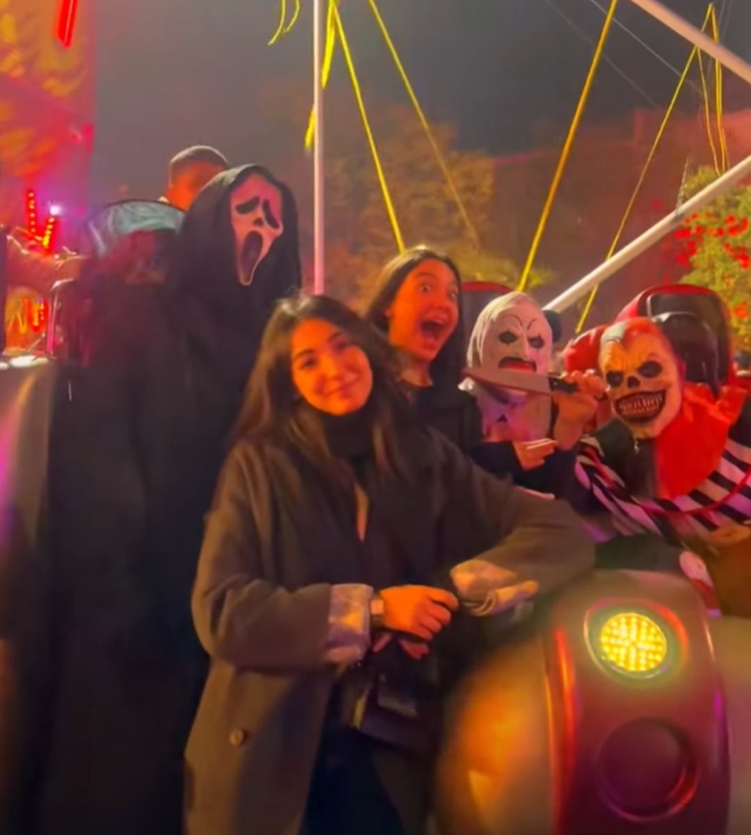 Persoane costumate la o petrecere de Halloween, printre decorațiuni și lumini colorate