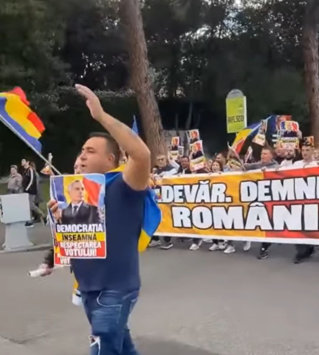 Participant la marșul din Roma cu un afiș de susținere pentru Călin Georgescu, în fața manifestanților cu steaguri românești